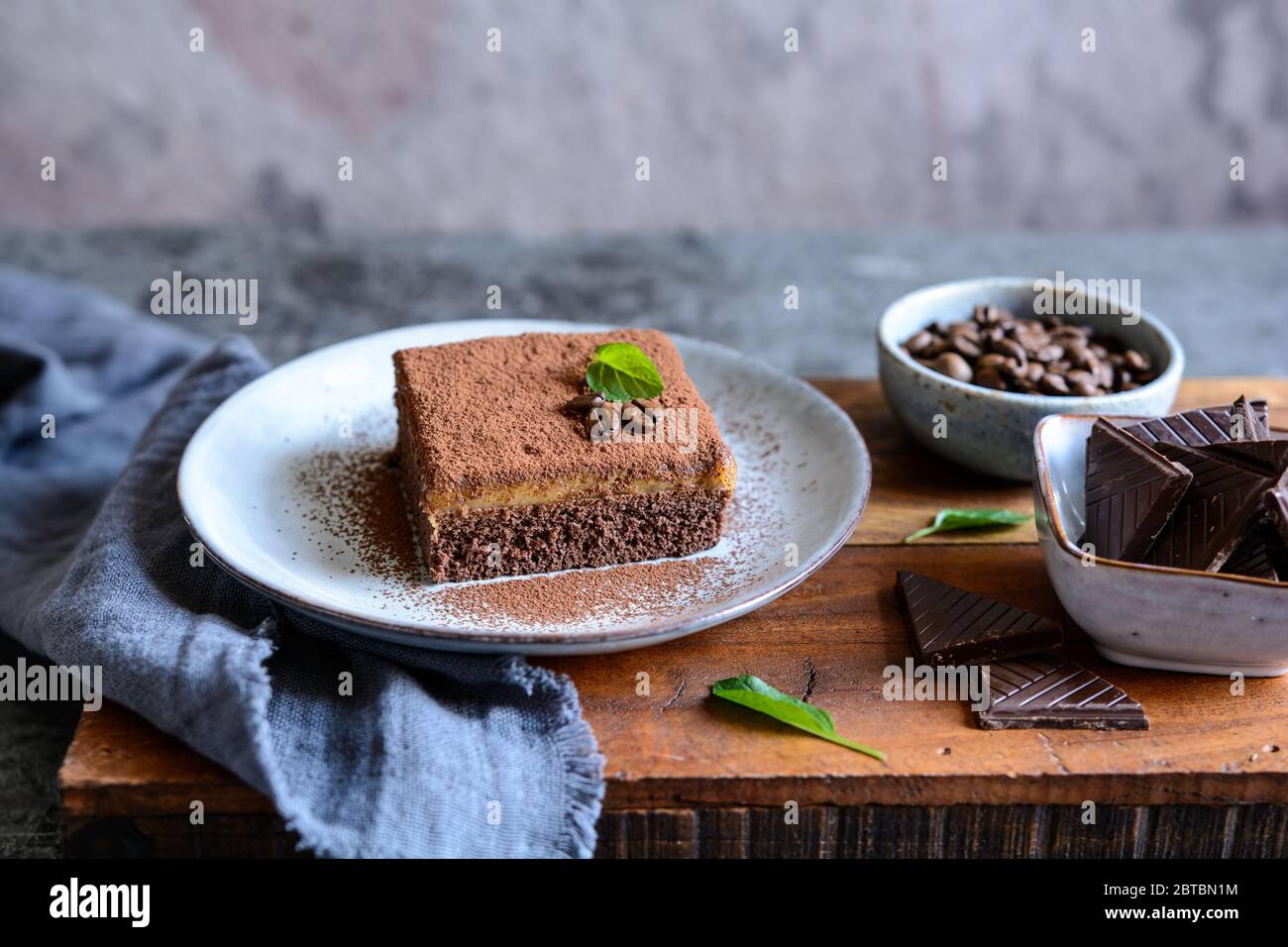 Dessert aus dunkler Schokolade mit Kaffeesahne und mit Kakaopulver auf einer Keramikplatte bestreut Stockfoto