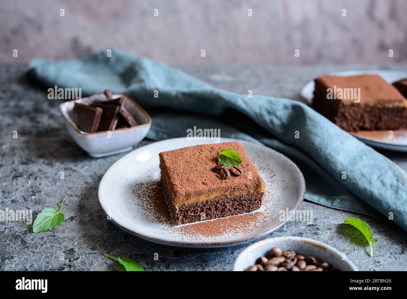 Dessert aus dunkler Schokolade mit Kaffeesahne und mit Kakaopulver auf einer Keramikplatte bestreut Stockfoto