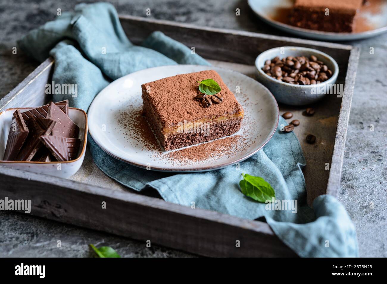Dessert aus dunkler Schokolade mit Kaffeesahne und mit Kakaopulver auf einer Keramikplatte bestreut Stockfoto