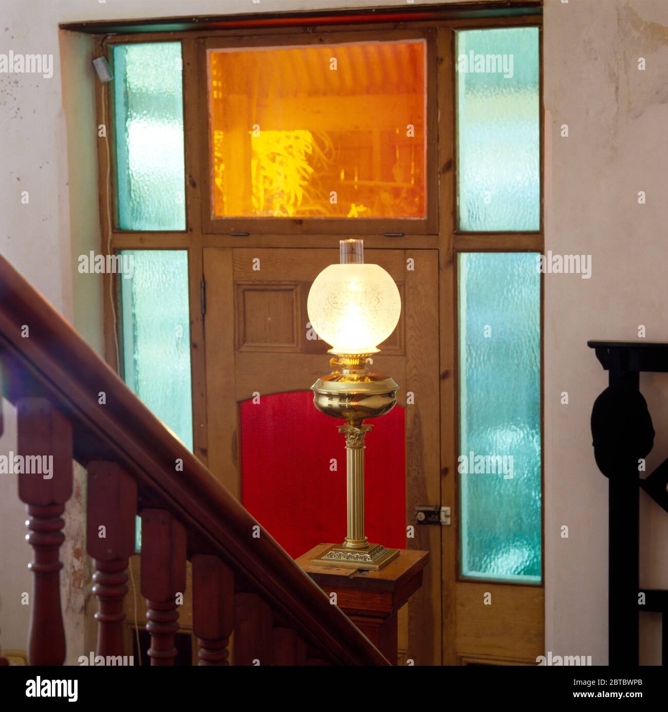 Glas und Messing Lampe im edwardianischen Stil auf einem Tisch vor einer Haustür mit Buntglasscheiben Stockfoto