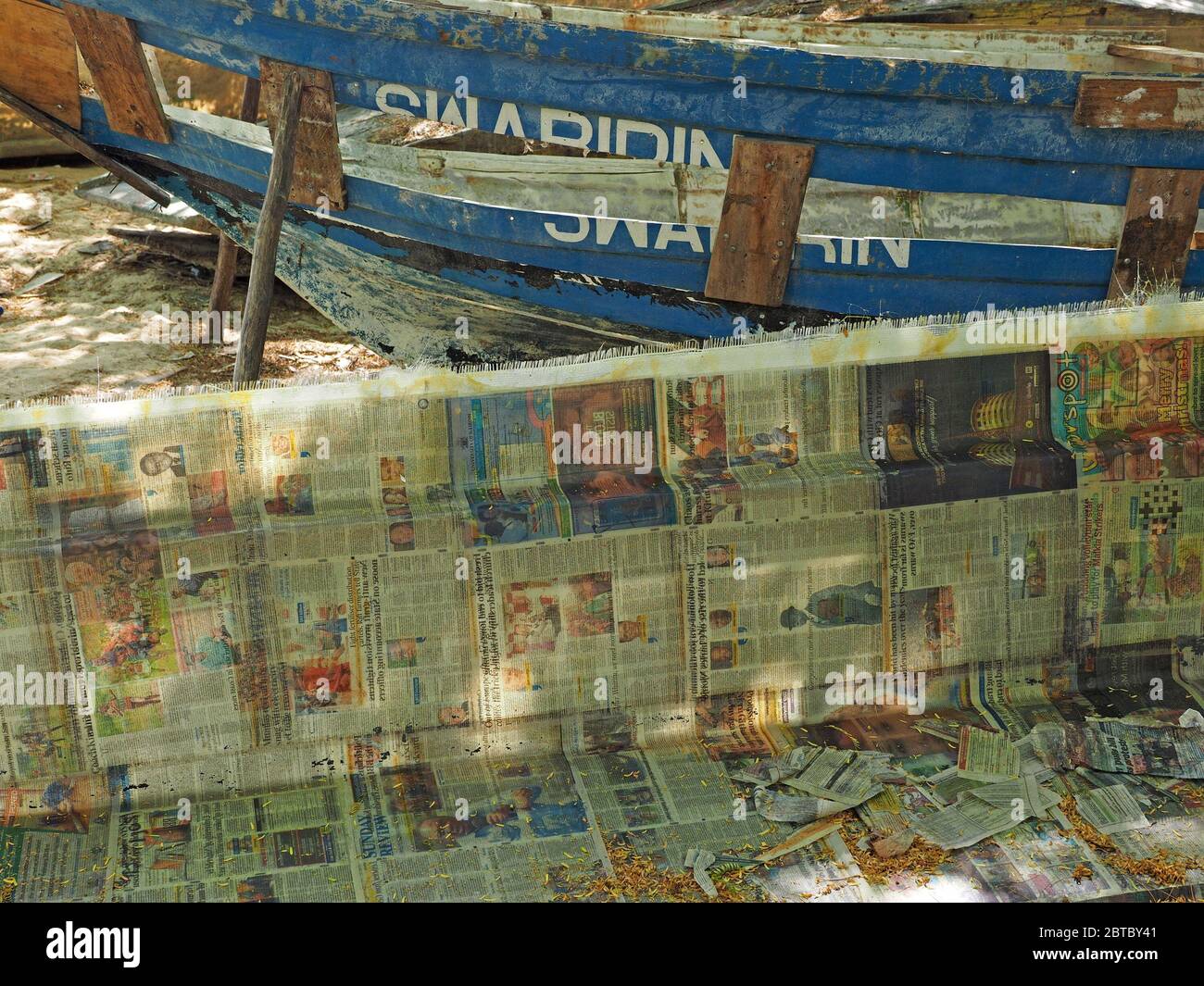 Moderne Glasfaser-Bootsbau mit Zeitungspapier kontrastiert mit Umbau der traditionellen hölzernen geschälten Schiff an Strand Bootswerft Malindi, Kenia, Afrika Stockfoto