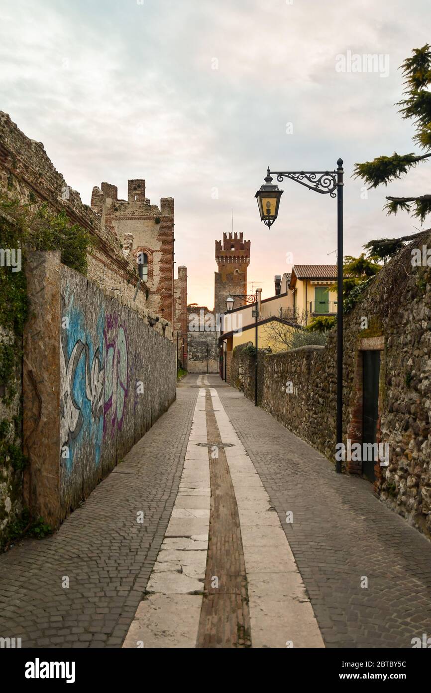 Eine schmale Gasse in der Altstadt mit der mittelalterlichen Skaliger Burg und der Stadtmauer, Lazise, Verona, Venetien, Italien Stockfoto