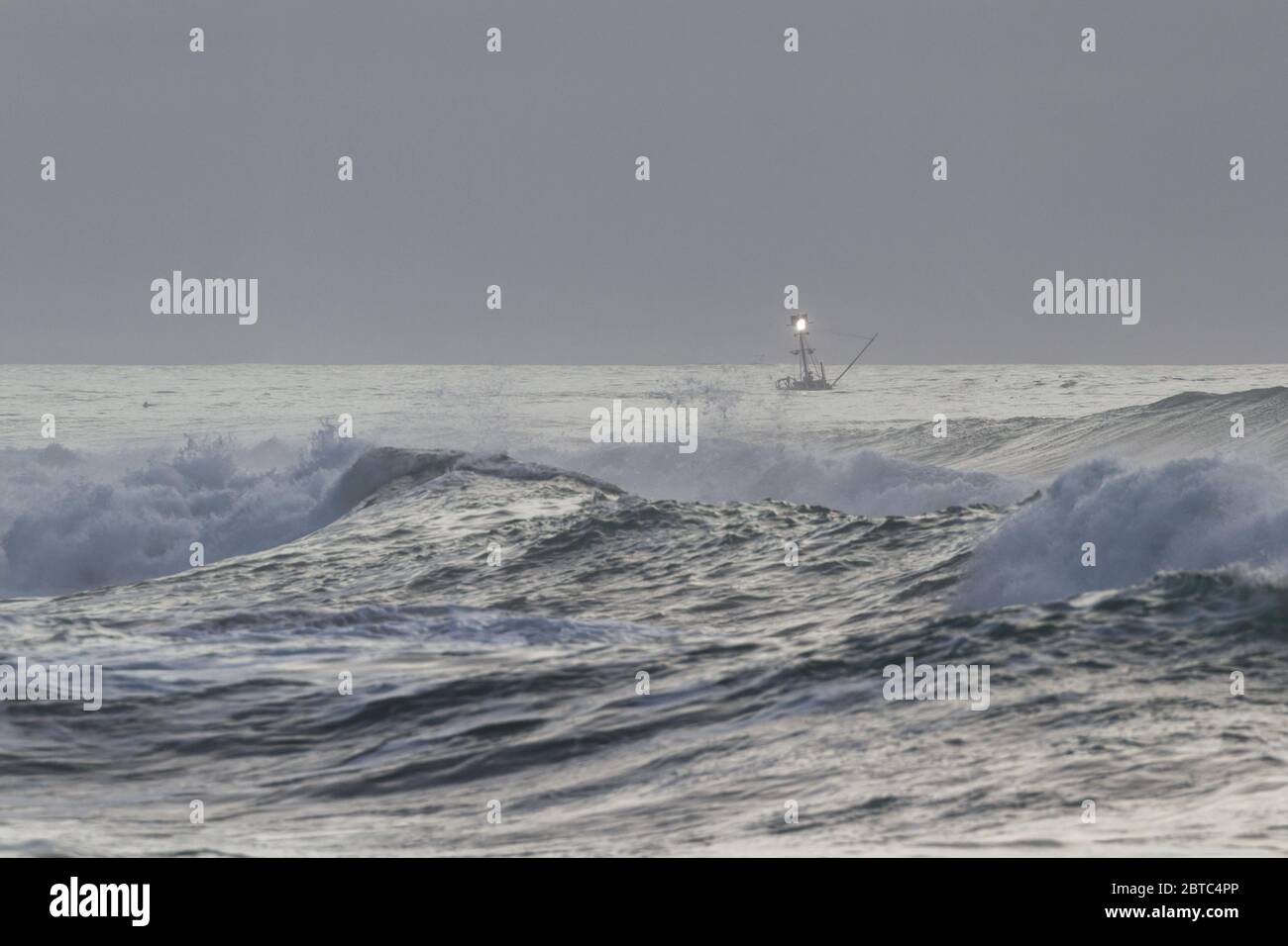 Angelcharter an der Küste von Oregon mit rauer See, da der Tag mit einer dicken Nebelbank im Hintergrund und einem trüben grauen Himmel endet Stockfoto