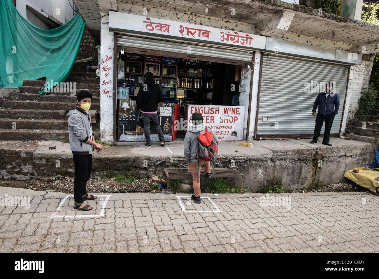 Männer tragen Schutzmaske und soziale Distanzierung im Spirituosengeschäft, um die Ausbreitung des Coronavirus COVID 19 zu verhindern. Mcleod Ganj, Dharamshala, Indien. Stockfoto