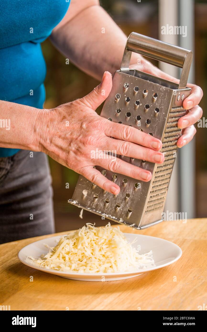 Frau reibe schweizer Käse als Pizza Belag verwendet werden Stockfoto