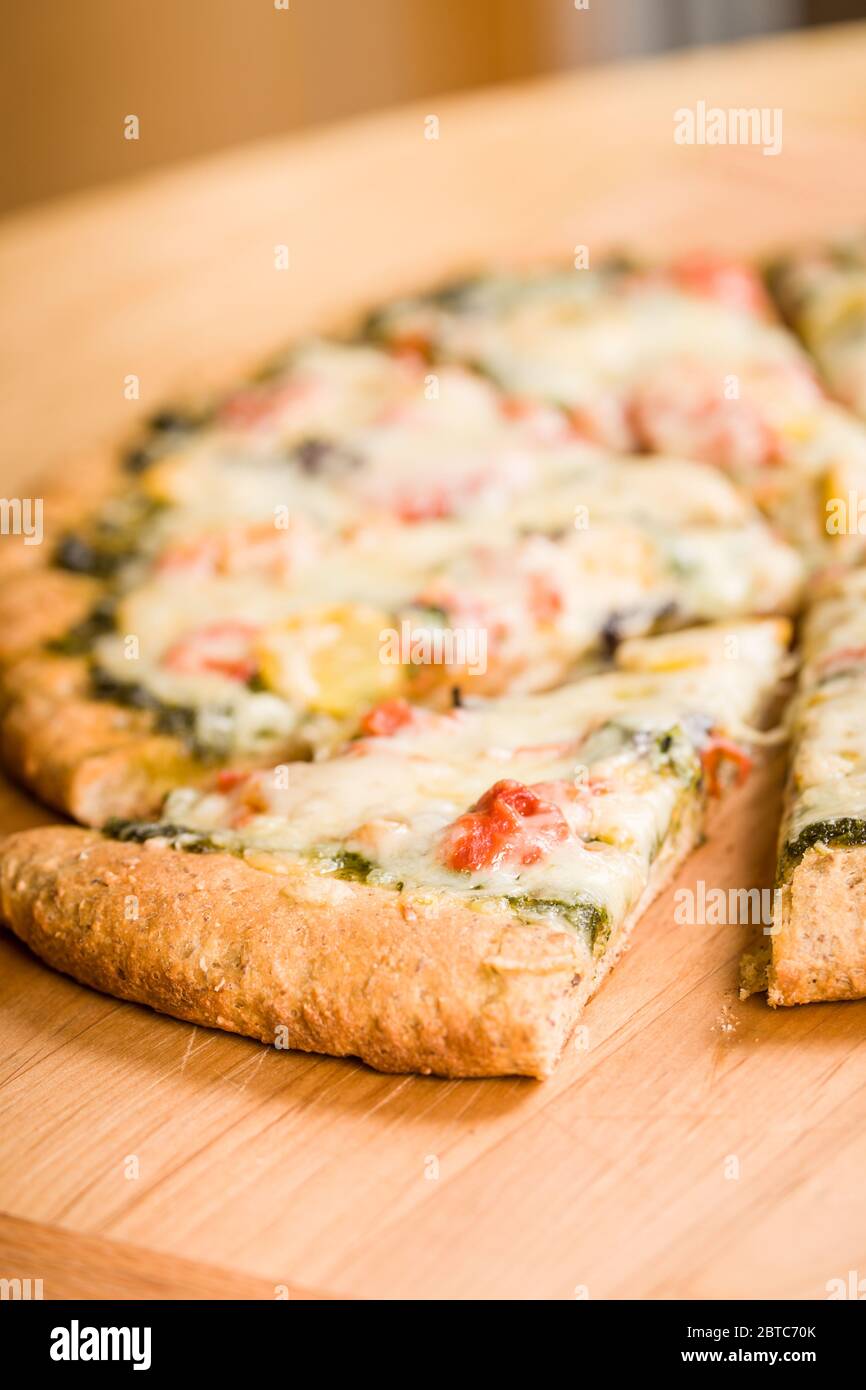 Frisch gebackene, vegetarische, Pesto, Multi-Grain, dicker Kruste Pizza in Scheiben geschnitten, fertig zum Essen Stockfoto