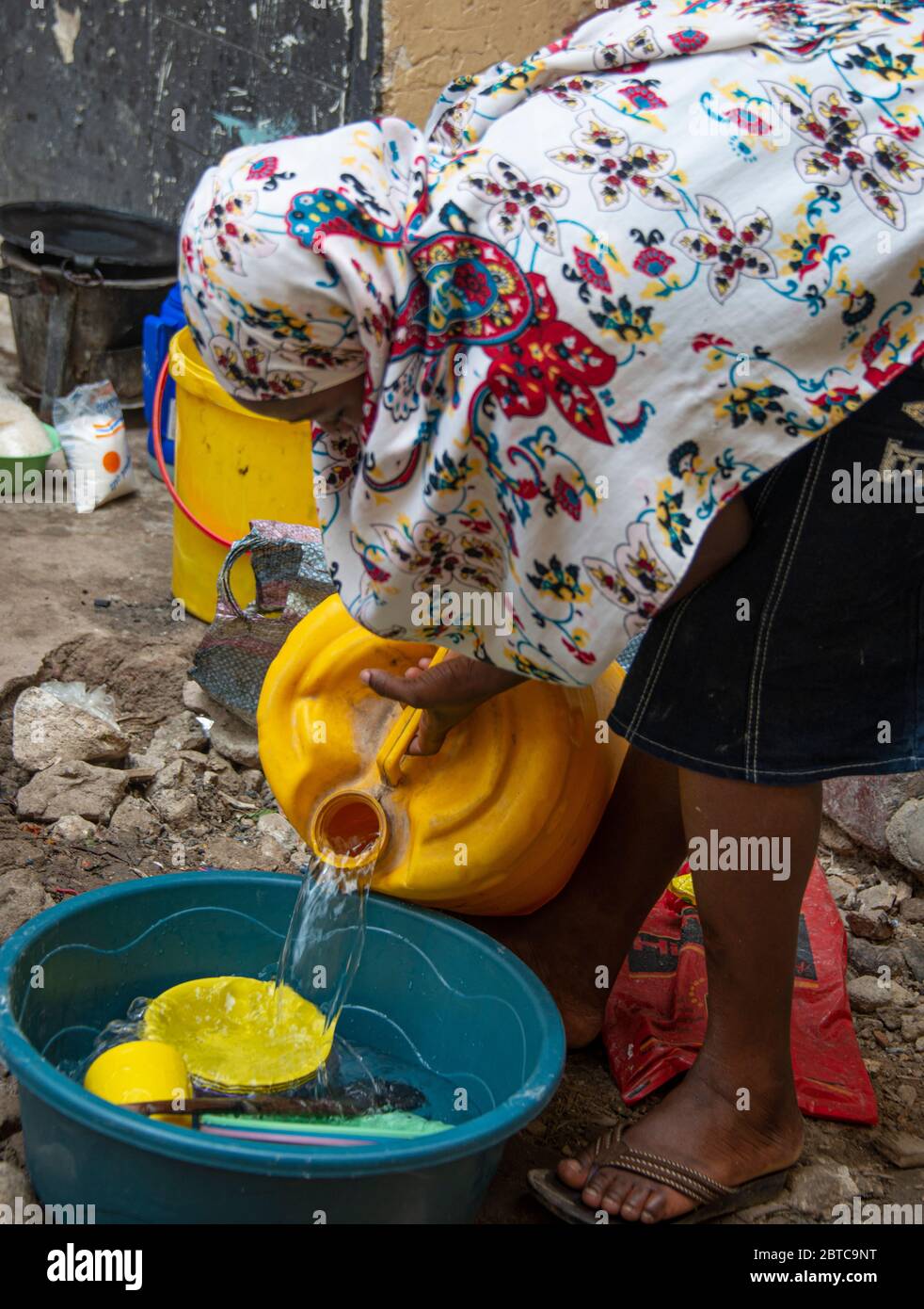 Frau, die Geschirr auf der Straße in Mombasa wäscht Stockfoto