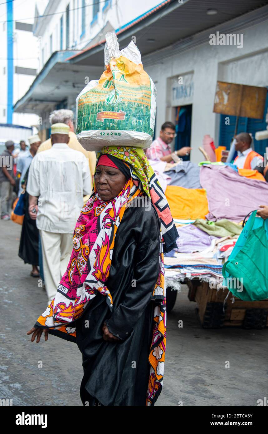 Frau mit Tasche auf dem Kopf auf einer Straße in Mombasa Stockfoto