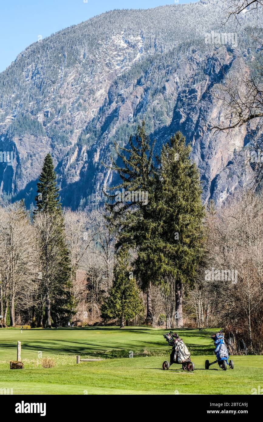 Zwei Golfertaschen auf Rad auf Golfplatz mit Berg im Hintergrund Stockfoto