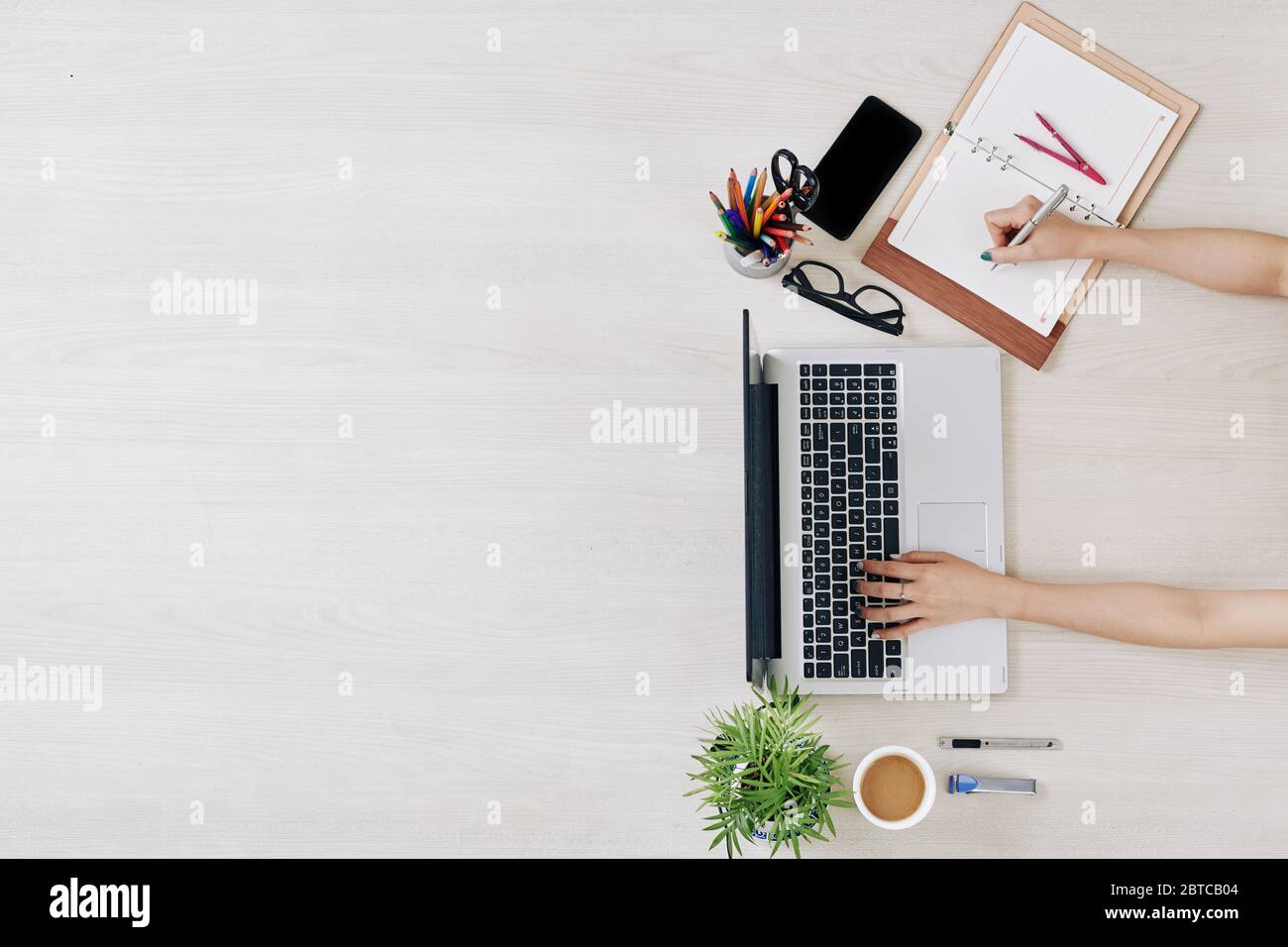 Geschäftsfrau, die während der Sperrung von zu Hause arbeitet, E-Mails überprüft und im Planer schreibt Stockfoto