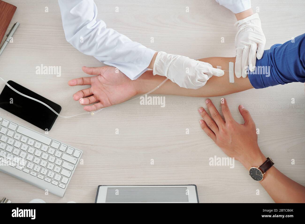 Krankenschwester, die Nadel mit Katheter in die Vene des Patienten für die Infusionstherapie einführt, Ansicht von oben Stockfoto