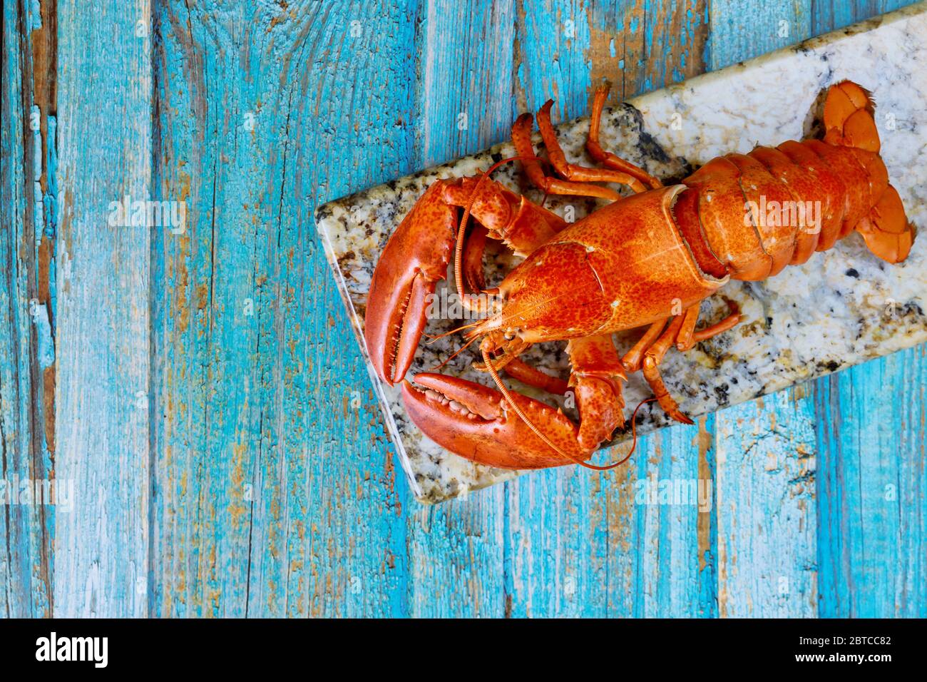Gedämpfter roter Hummer auf einem Holzbrett mit auf einem Schieferteller Stockfoto