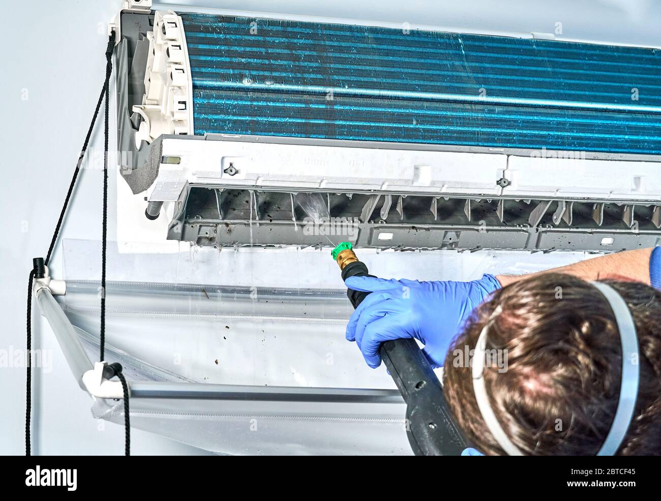 Montreal, Kanada - 24. Mai 2020: Ingenieur in blauen Handschuhen und Maske Reinigung Gree schmutzige Klimaanlage von Staub und Schimmel mit Wasser-Staubsauger. Gr Stockfoto