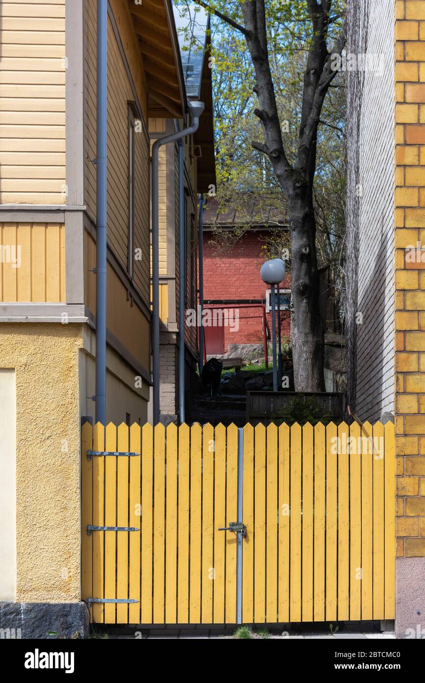 Gelber Plankenzaun zwischen alten Holzhäusern in der Linnankatu Straße in Turku Finnland Stockfoto