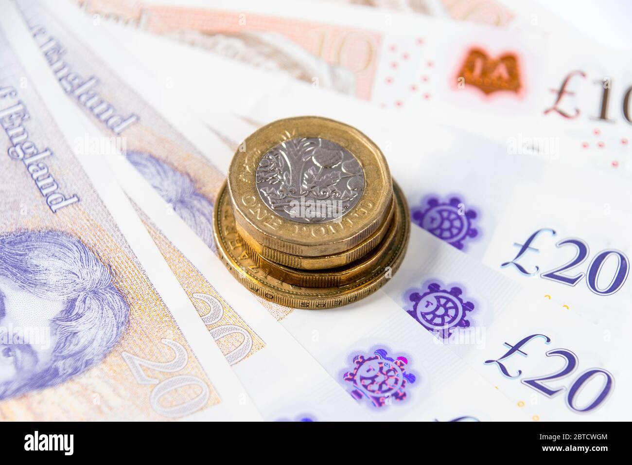 Nahaufnahme einer Pfund-Münze auf Polymer-Währungsbezeichnung von zehn und zwanzig im Hintergrund Stockfoto