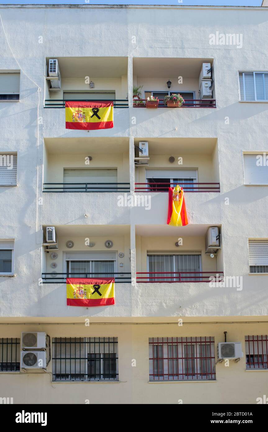 Badajoz, Spanien - 18. Mai 2020: Spanische Flaggen mit einem schwarzen Band hängen über Balkonen. Tribut an die Opfer von Covid-19 Stockfoto