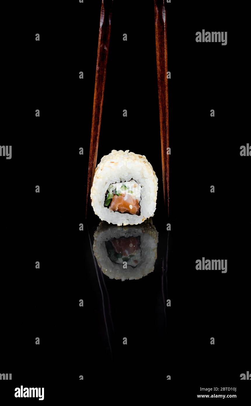 Sushi Rolle philadelphia in Sesam mit Lachs auf schwarzem Hintergrund. Asiatische Restaurantkarte. Vorlage Mockup, Platz für Text. Stockfoto