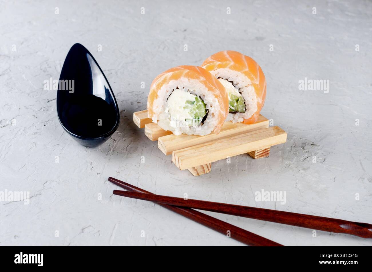 Sushi philadelphia auf Holzteller, Sojasauce und Essstäbchen auf einem grauen Betontisch. speisekarte des restaurants sian. Lieferservice Japanisches Essen. Templat Stockfoto