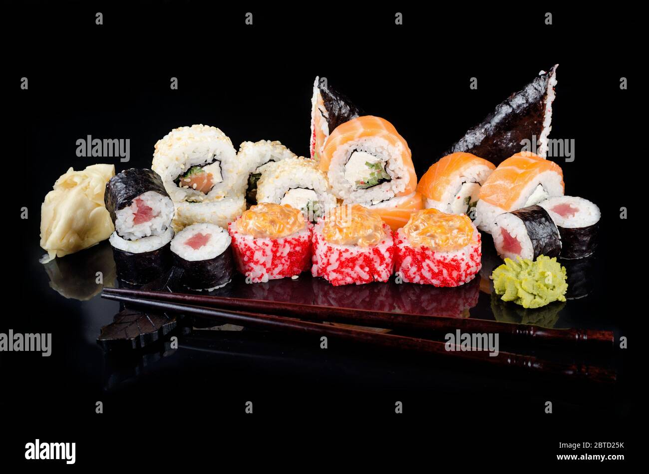 Verschiedene Sushi-Brötchen, Sojasoße, Ingwer, Wasabi und Essstäbchen auf einem schwarzen Tisch. Asiatisches Restaurant, Sushi-Menü. Lieferservice Japanisches Essen Stockfoto