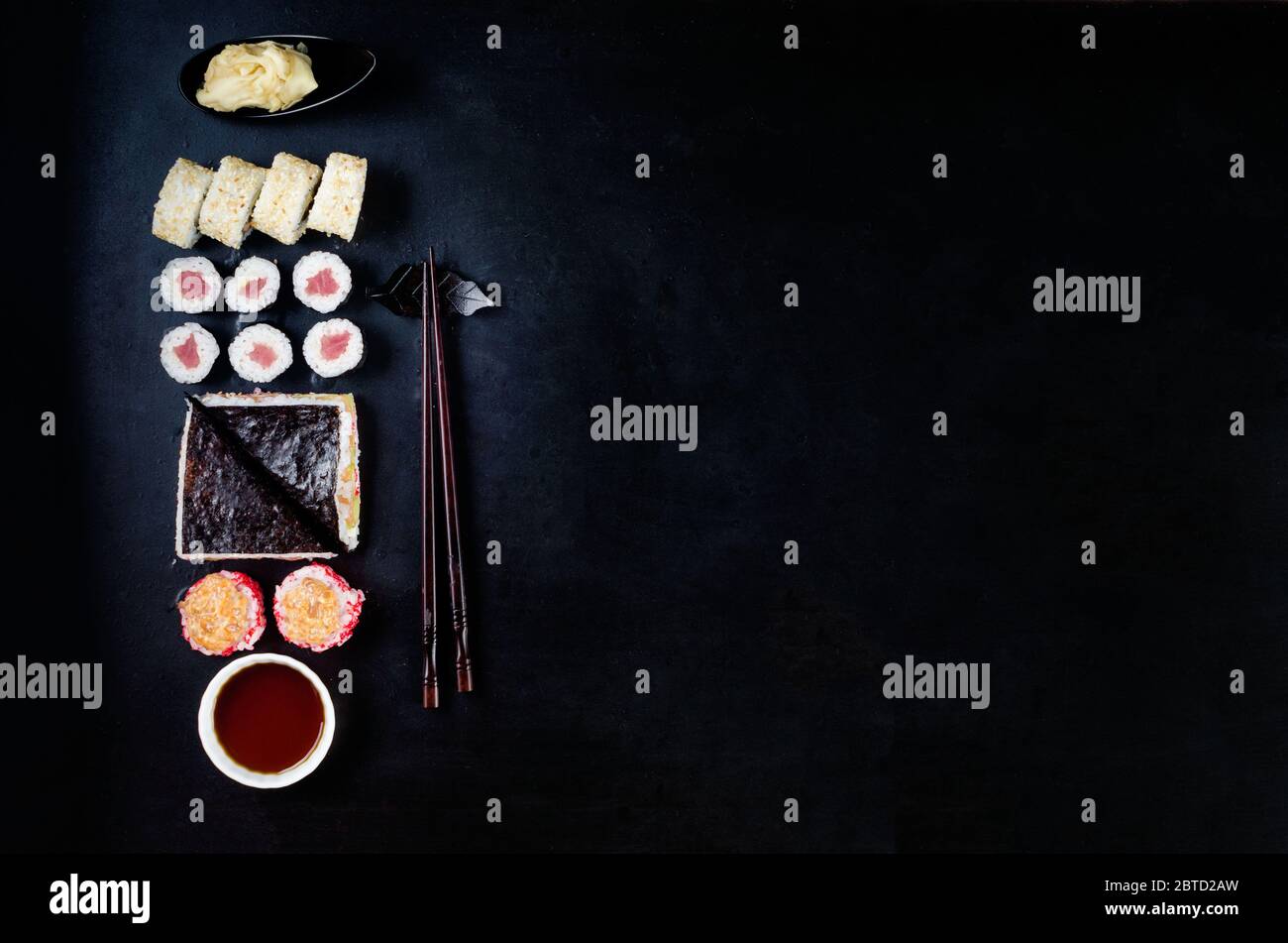 Verschiedene Sushi-Brötchen, Sojasoße, Ingwer, Wasabi und Essstäbchen auf einem schwarzen Tisch. Asiatisches Restaurant, Sushi-Menü. Lieferservice Japanisches Essen Stockfoto