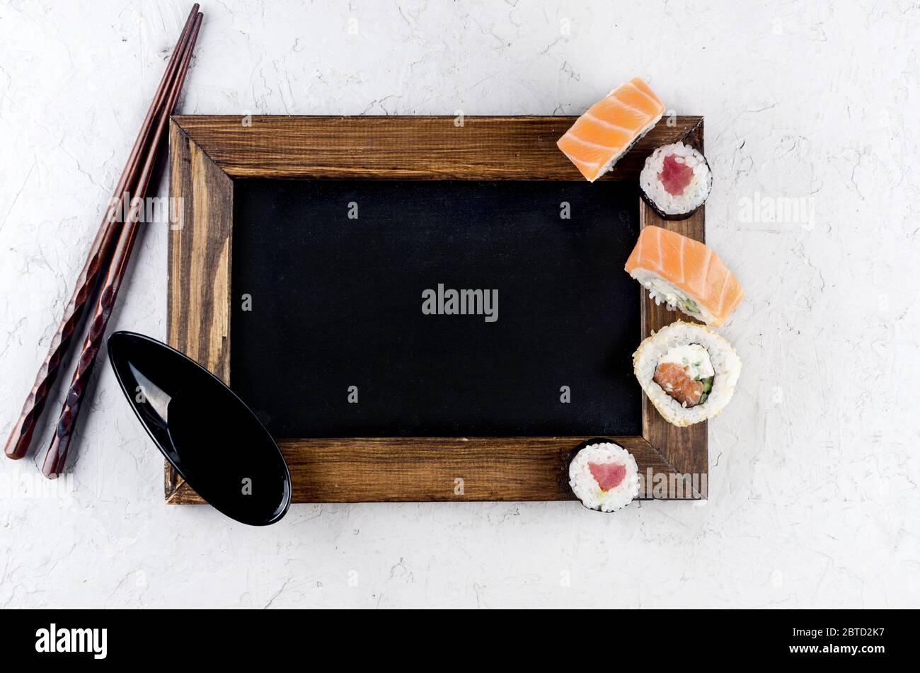 Verschiedene Sushi und Brötchen mit Sojasoße, Ingwer, Wasabi und Essstäbchen auf einem grauen Betontisch. Sushi-Menü. Lieferservice Japanisches Essen. Stockfoto