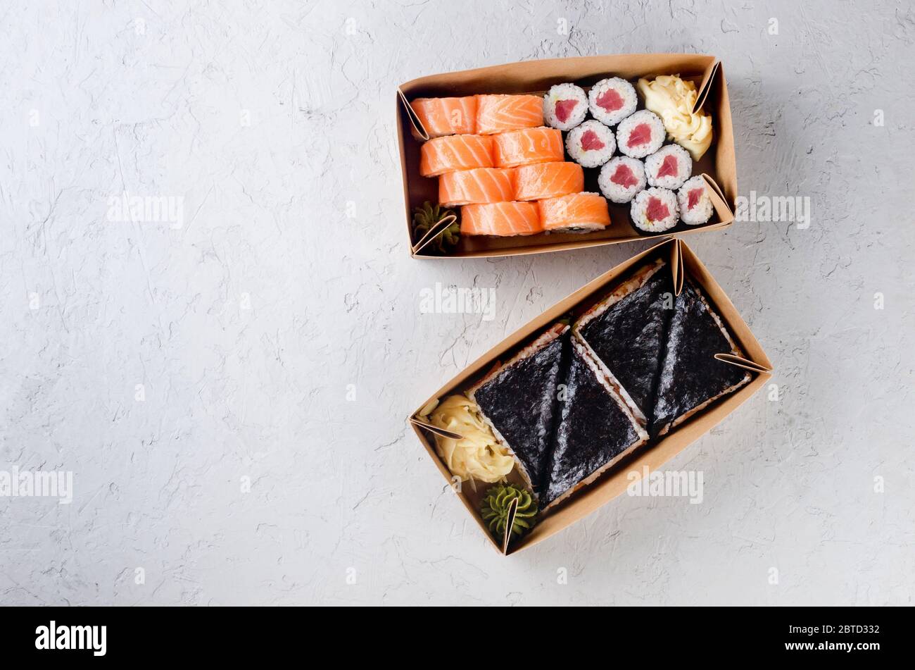 Leckere Sushi-Rollen in Einweg-Kraftpapier-Boxen, Sauce auf dunklem Tisch. Konzept Lieferservice Japan Lebensmittel in Öko-Container. Flaches Lay, Schablone Mocku Stockfoto