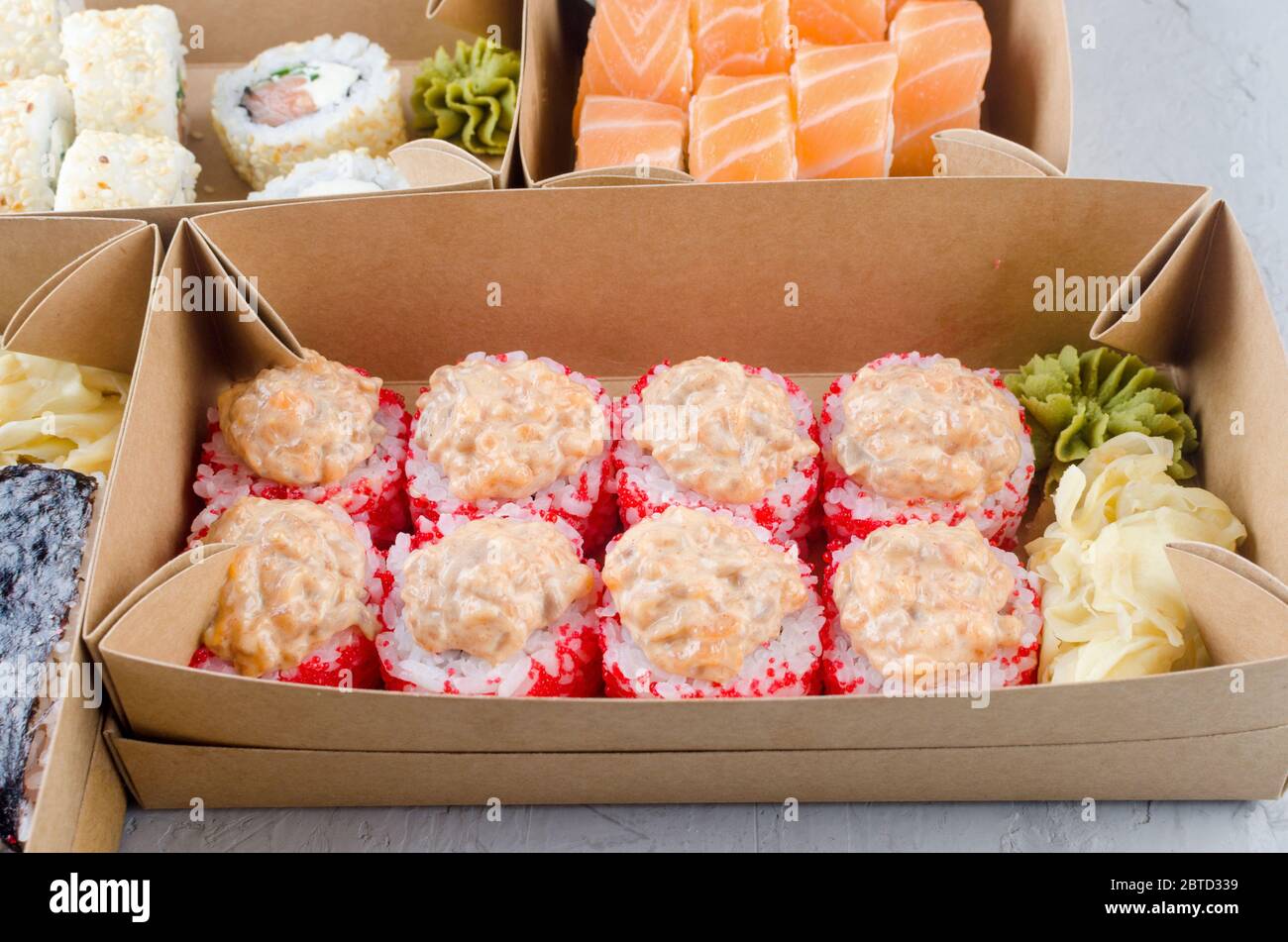 Leckere Sushi-Rollen in Einweg-Kraftpapier-Boxen, Sauce auf dunklem Tisch. Konzept Lieferservice Japan Lebensmittel in Öko-Container. Flaches Lay, Schablone Mocku Stockfoto