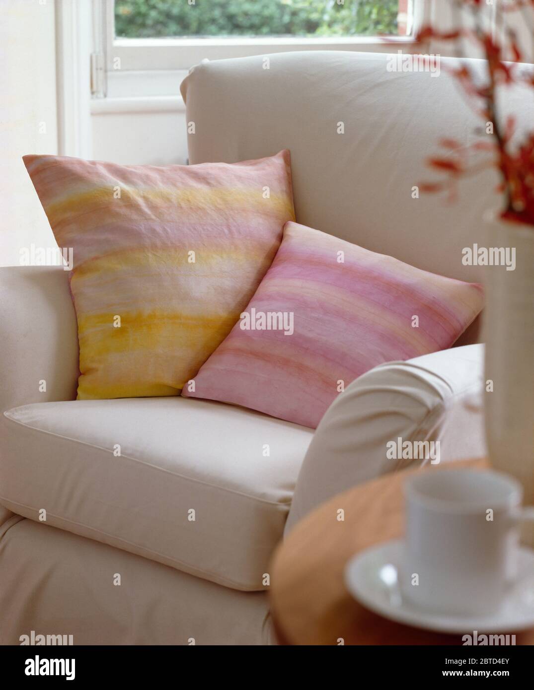 Kissen in Pastellrosa und Yello mit Krawatte auf weißem Sessel Stockfoto