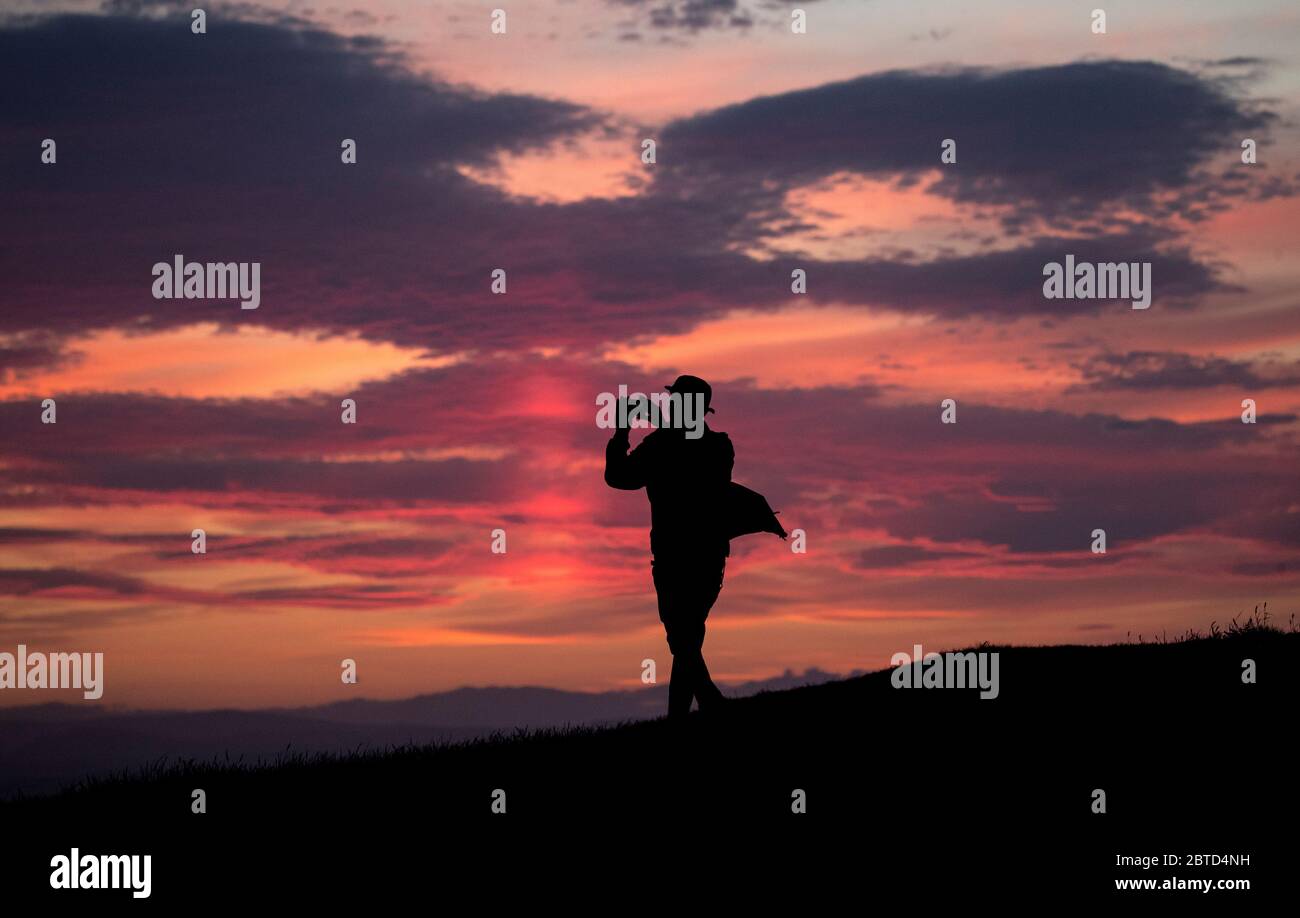 Ein Mann nimmt mit einem Handy den Sonnenuntergang von Calton Hill, Edinburgh, auf. Stockfoto