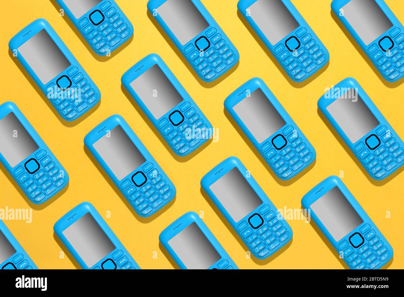 Buntes blaues Handy-Hintergrundmuster mit wiederholten Handy-Symbolen in diagonalen Reihen über einem hellen gelben Hintergrund Stockfoto