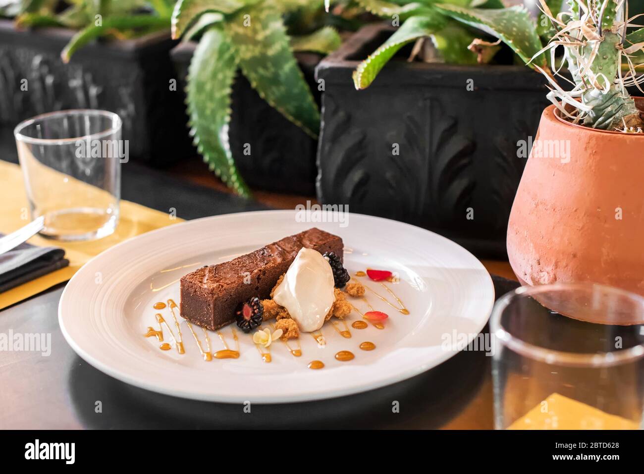 Servierteich aus Schokolade und Eis, garniert mit Nüssen und auf einem weißen Teller am Tisch in einem Restaurant serviert Stockfoto