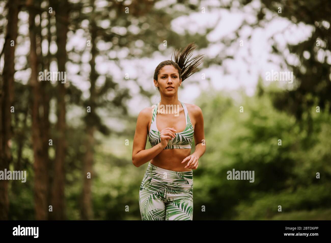 Hübsche junge Fitness-Frau läuft auf dem Waldweg Stockfoto