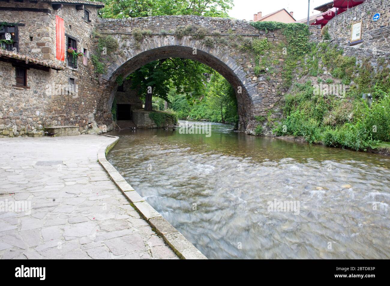 Der Fluss Quiviesa fließt unter einer alten Steinbrücke in Potes, Kantabrien, Spanien. Stockfoto
