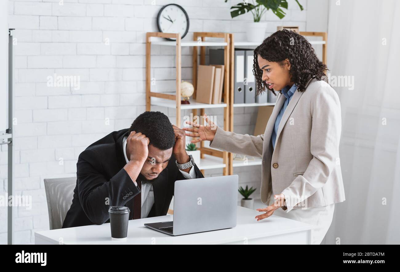 Frustrierter afroamerikanischer Chef schimpft jungen Untergebenen für Fehler in Business-Projekt im Büro machen Stockfoto
