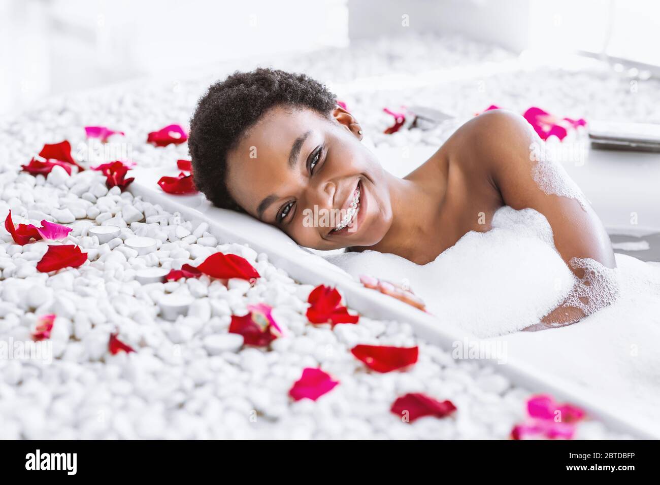 Spa-Tag und Beauty-Pflege zu Hause. Frau nimmt Bad mit Schaum und Blütenblättern Stockfoto