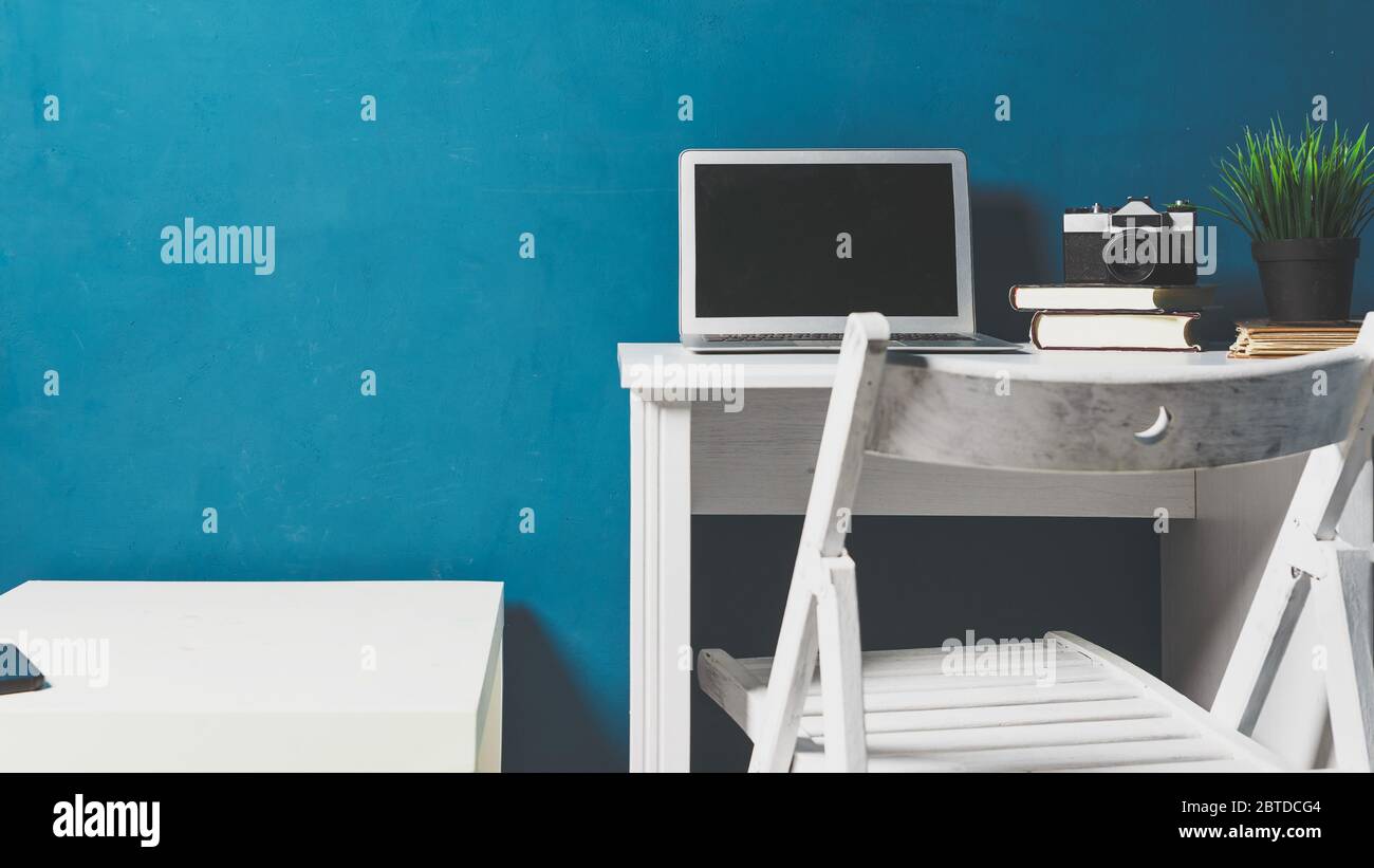 Leerer Arbeitsplatz. Arbeiten Sie von zu Hause aus. Notizbuch, Bücher und Bleistifthalter auf dem Tisch auf blauem Hintergrund. Moderne Arbeitsumgebung und Remote Stockfoto