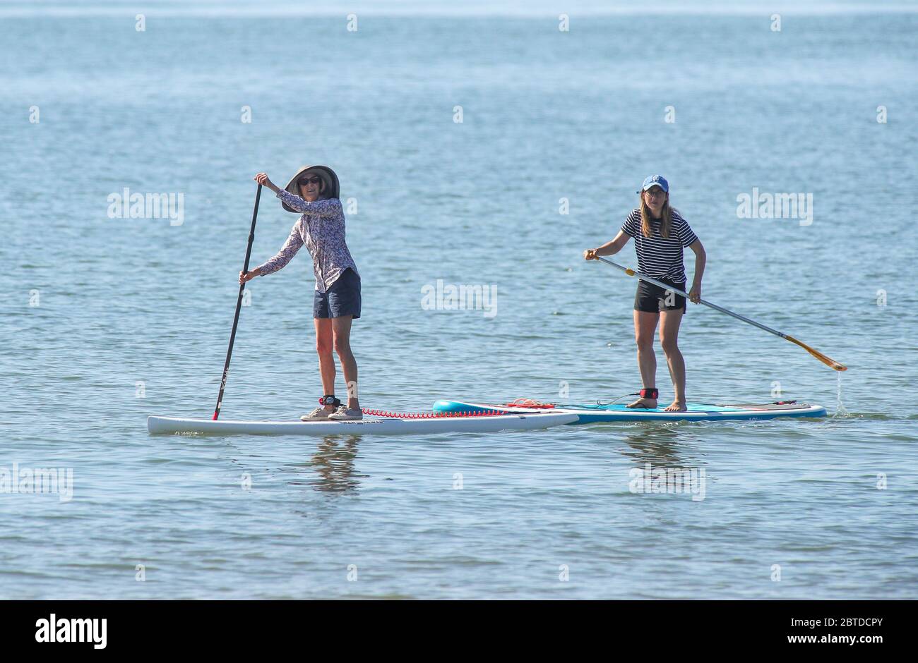 Southampton, Hampshire, Großbritannien. Mai 2020. Wetter in Großbritannien. Zwei Damen paddeln auf dem Solent mit der Isle of Wight im Hintergrund an einem heißen Feiertagsmontagmorgen in Calshot Beach. Credit Stuart Martin/Alamy Live News Stockfoto