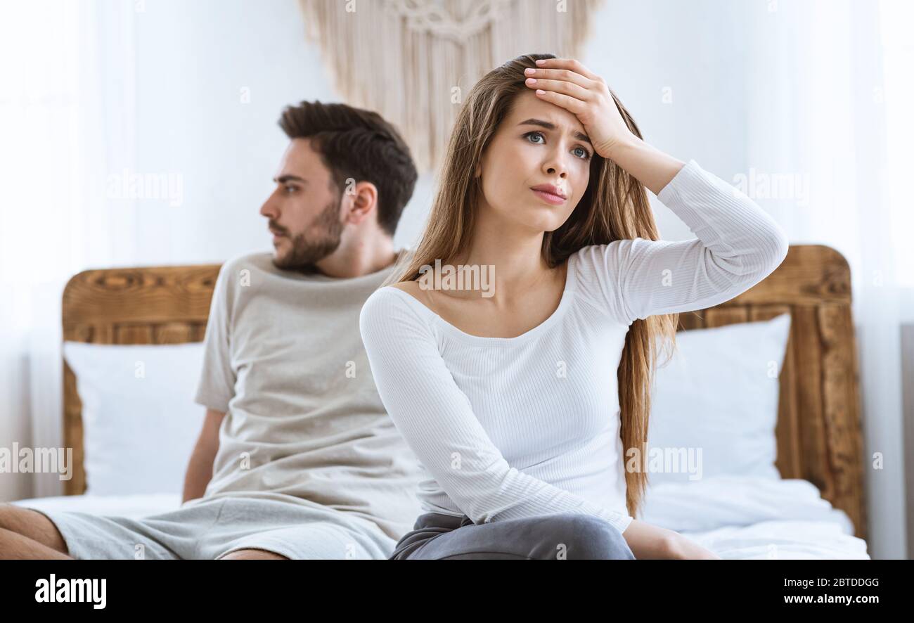 Beleidigte Ehepartner haben sich von einander abgewandt und im Schlafzimmer auf dem Bett gesessen Stockfoto