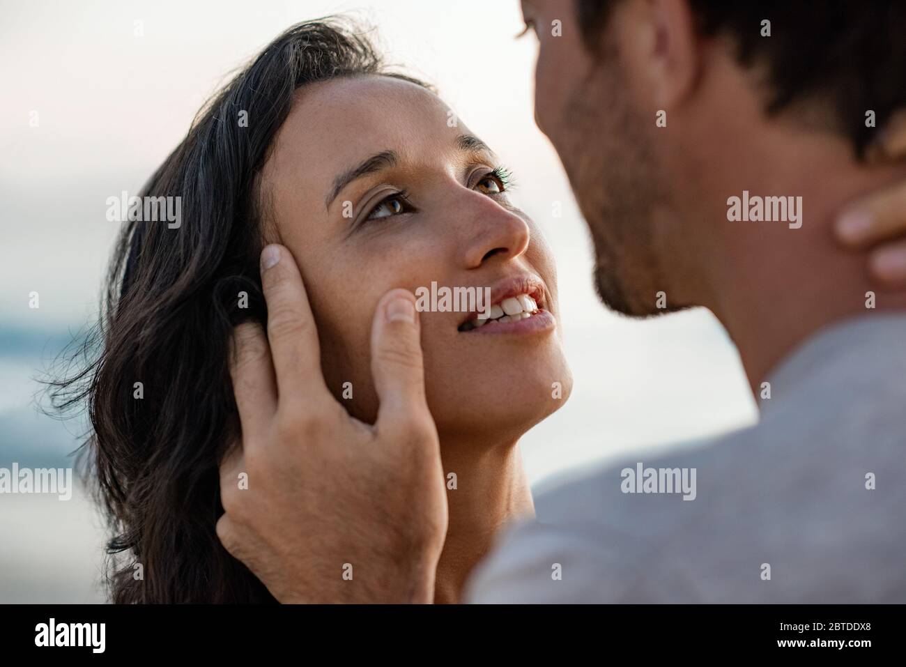 Liebevolle Frau starrt ihrem Mann in die Augen am Strand Stockfoto