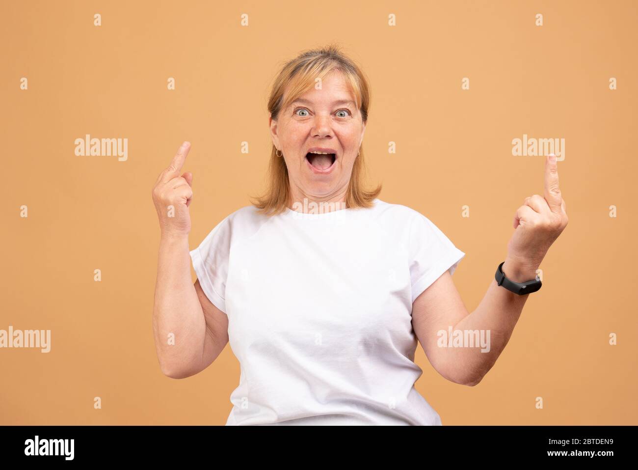 Coole ältere Dame in weißem T-Shirt macht Mittelfinger Zeichen Stockfoto