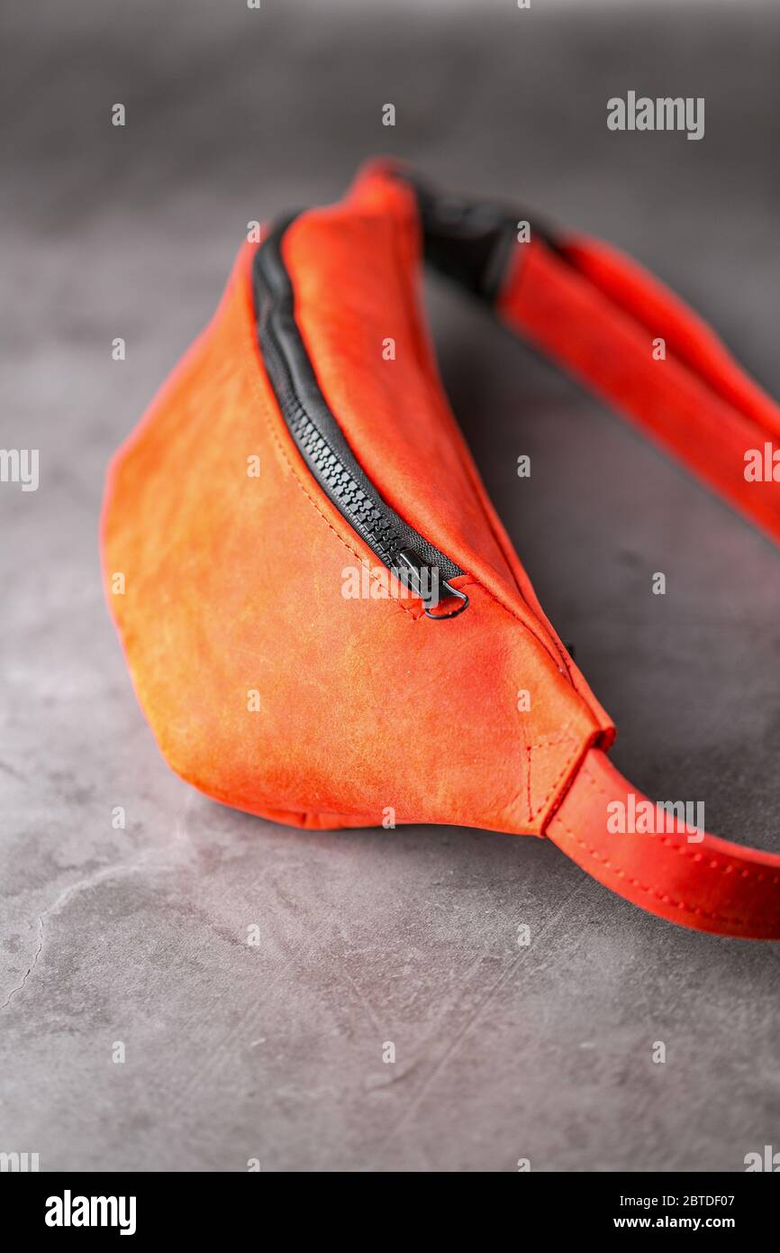 Rote Hüfttasche aus Leder, Banane auf grauem Hintergrund. Handgefertigt Stockfoto