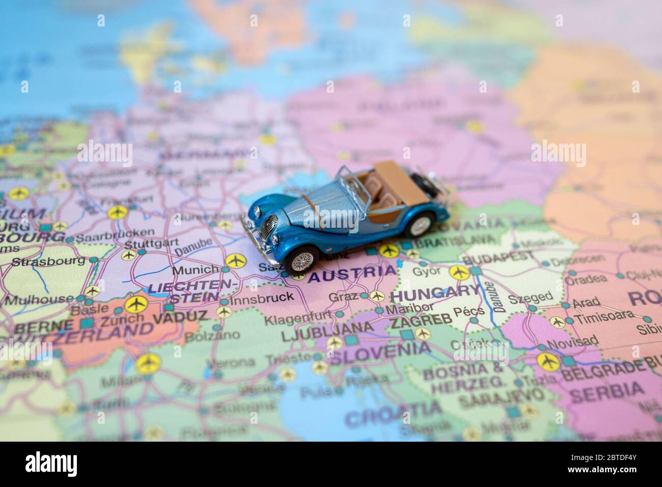 Kleines Spielzeug Retro Auto auf Europa Karte in Österreich. Anreise mit dem Auto Konzept. Stockfoto