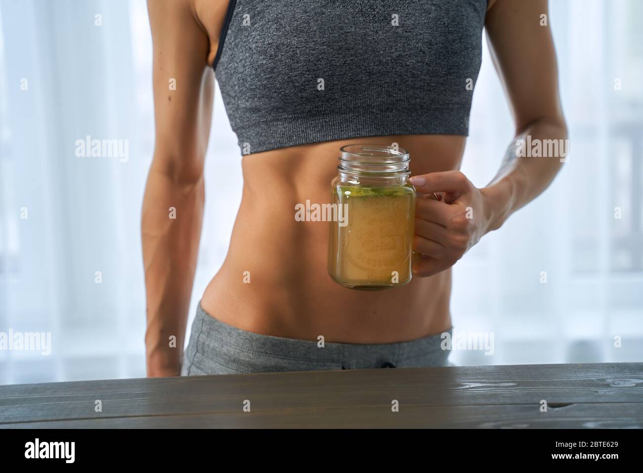 Frau, die ein heißes Getränk trinkt. Sportliche Frau mit einer Tasse Knochen Brühe Stockfoto