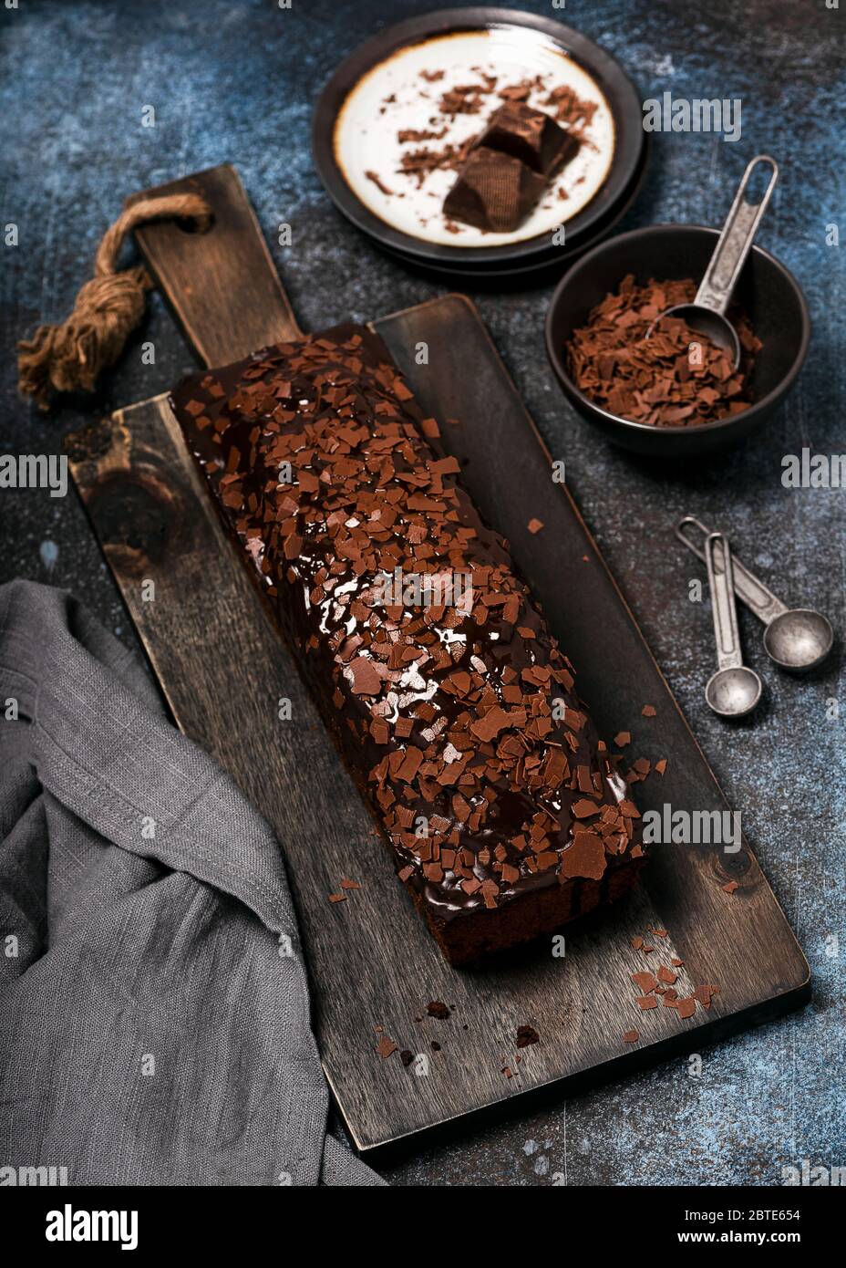 Köstliche hausgemachte Schokoladenkuchen mit Chips Topping und Glasur auf rustikalen Holz Schnittbrot. Selektiver Fokus. Stockfoto