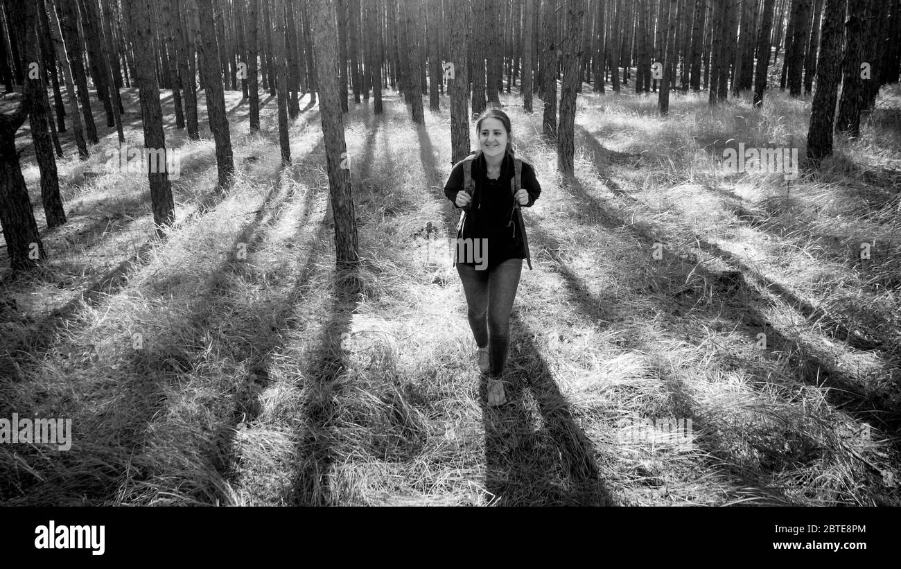 Schwarz-Weiß-Foto von lächelnden jungen Frau mit Rucksack Wandern im Wald Stockfoto