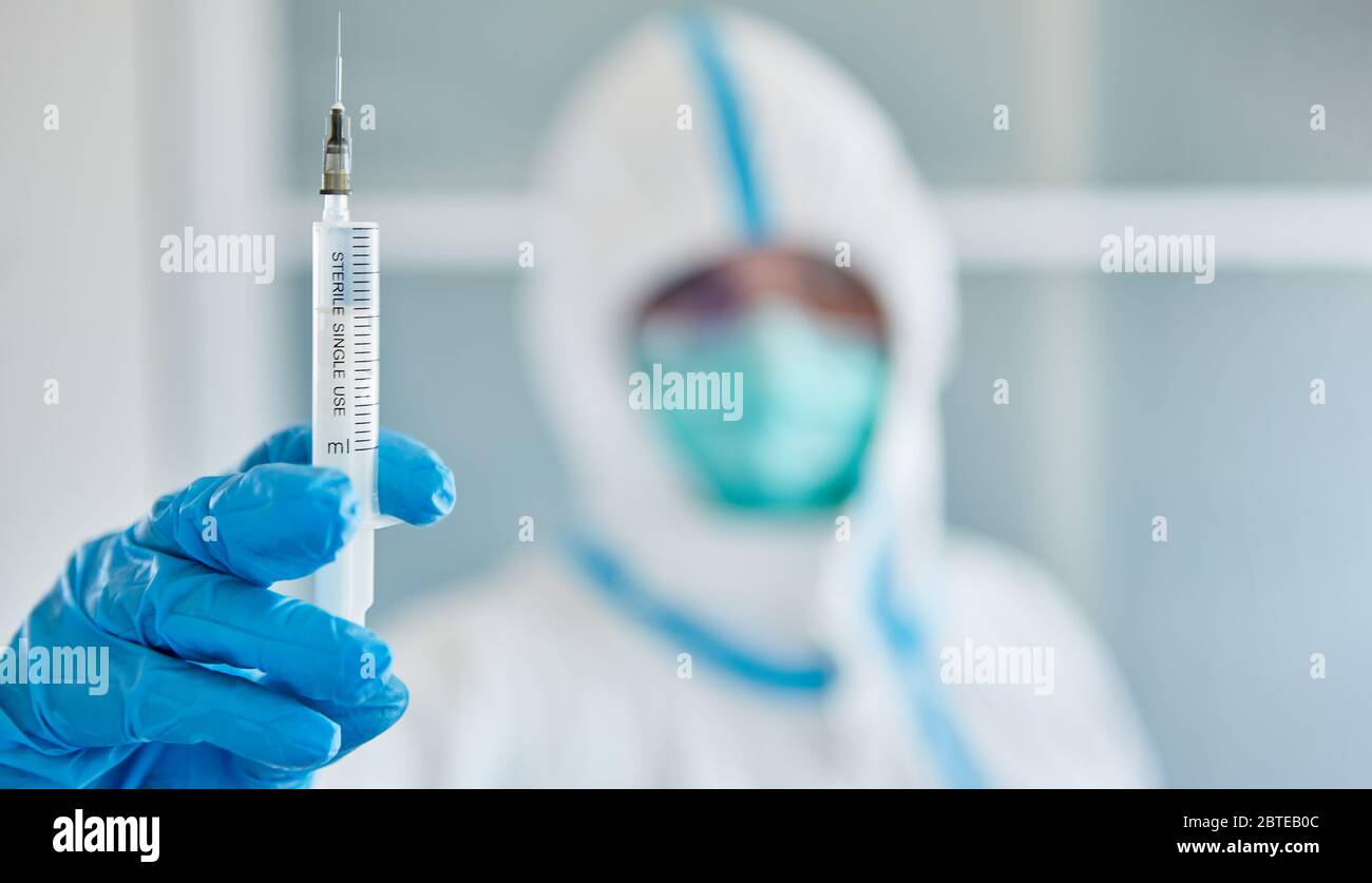 Forscher in Schutzkleidung im Labor hält Spritze gegen Covid-19 und Coronavirus zu impfen Stockfoto