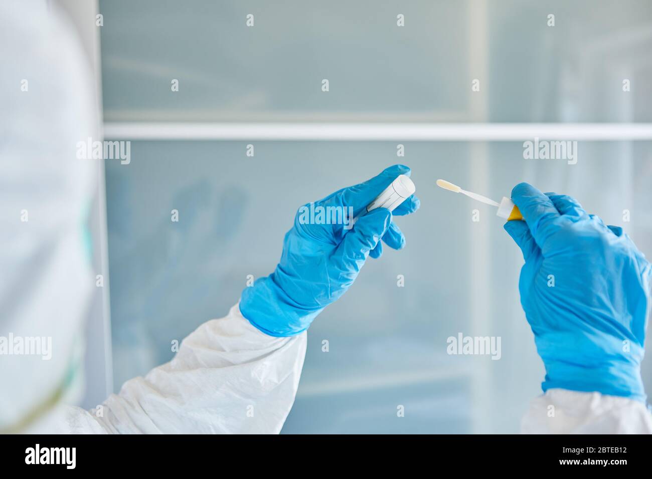 Medic in Schutzkleidung verpackt Rachenabstrich für Speichelprobe während Coronavirus-Test Stockfoto