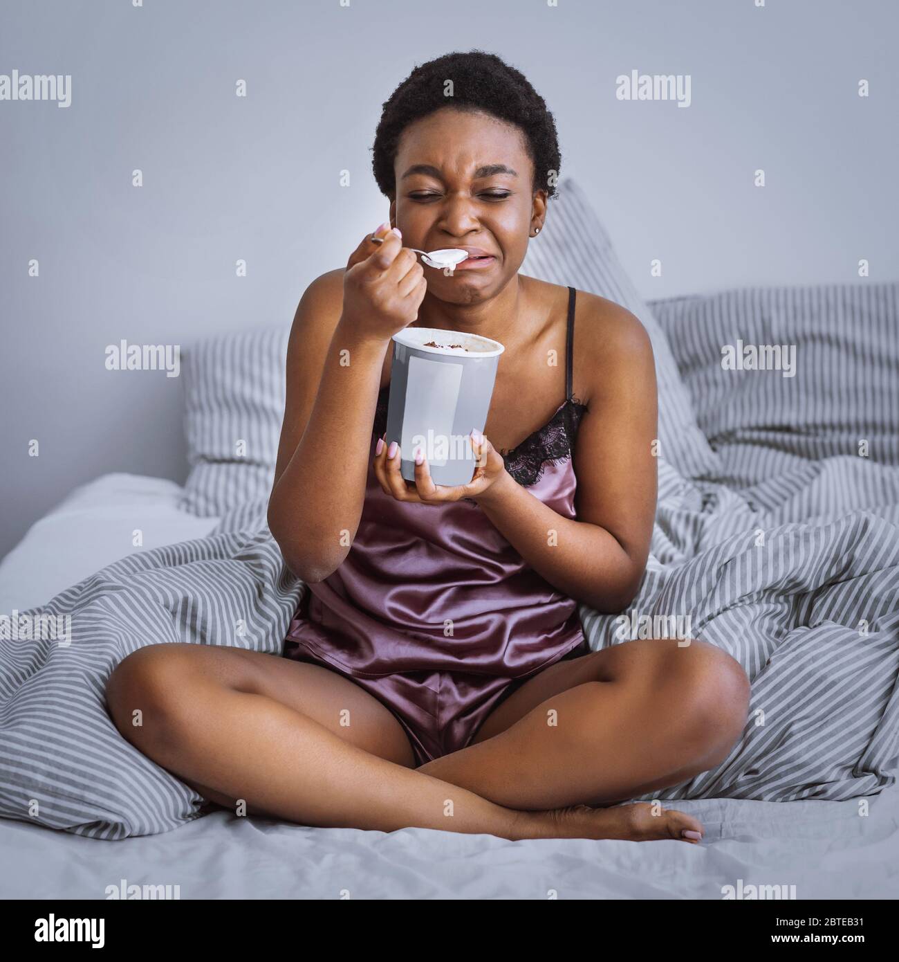 Zerfall Konzept. Weinendes Mädchen, das Eis im Bett isst Stockfoto