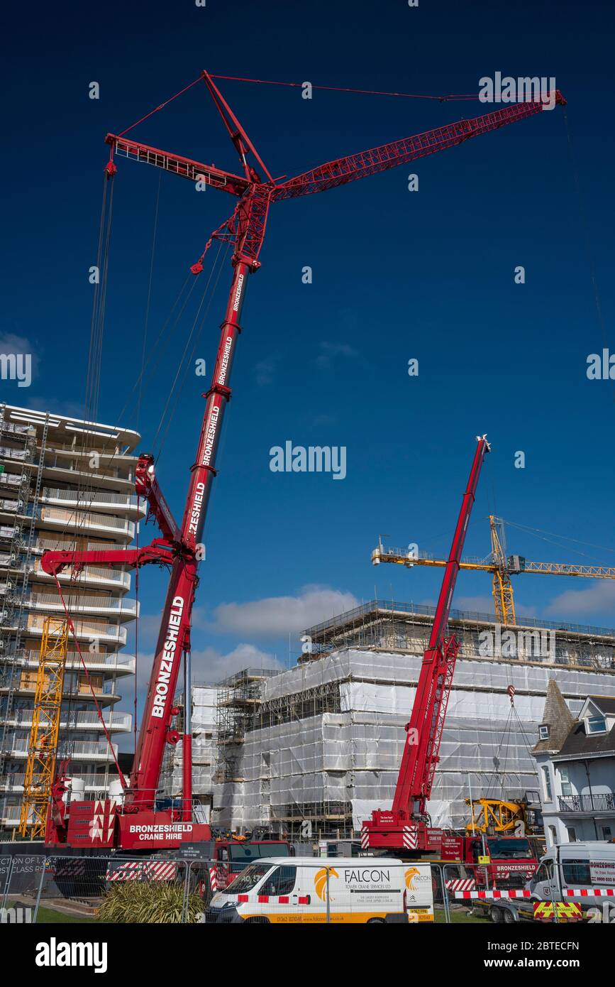 Ein massiver Kran, der einen großen Kran auf einer Baustelle demontiert. Stockfoto