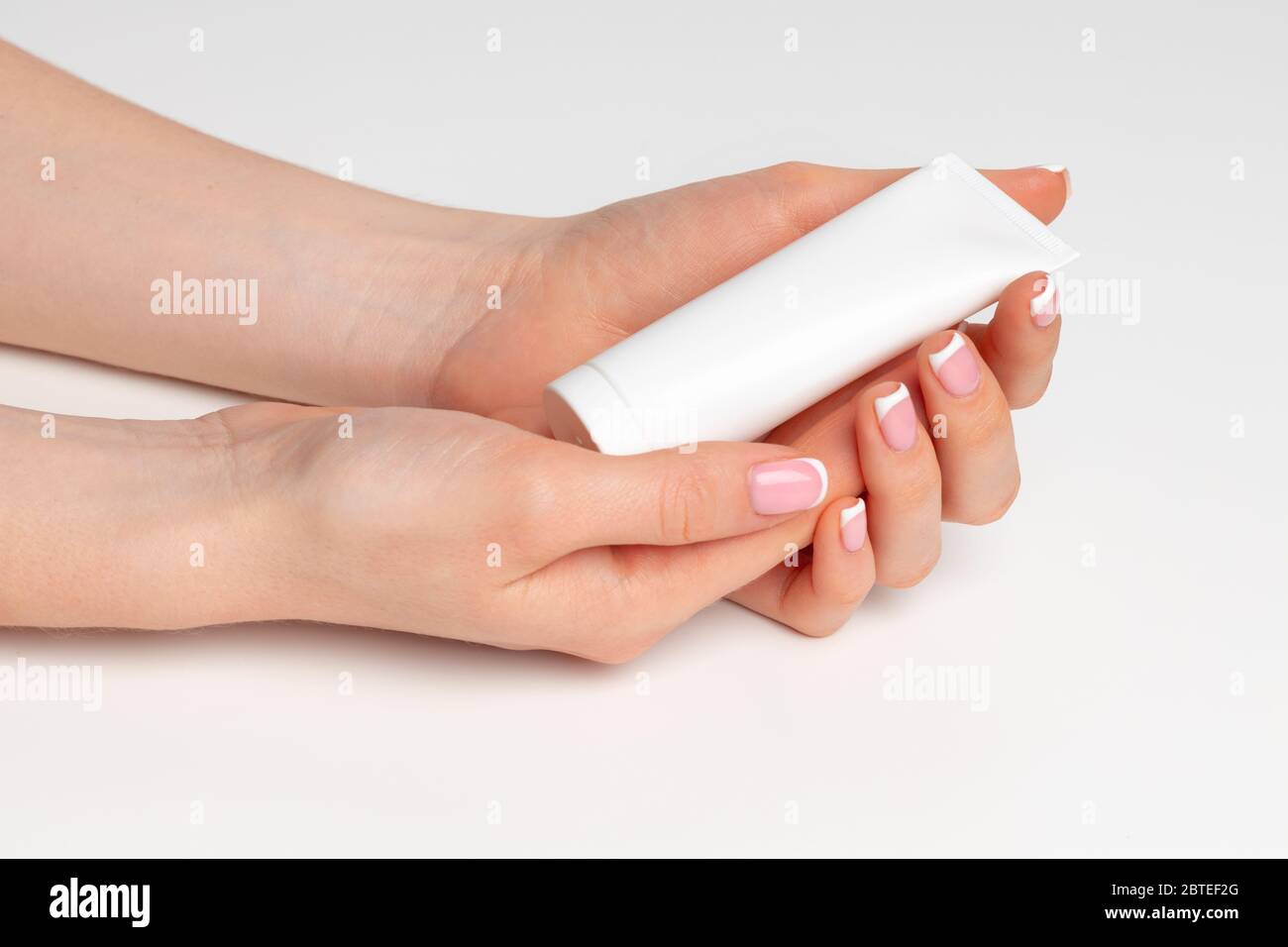 Weibliche Hand hält kosmetische Flasche auf weiß Stockfoto